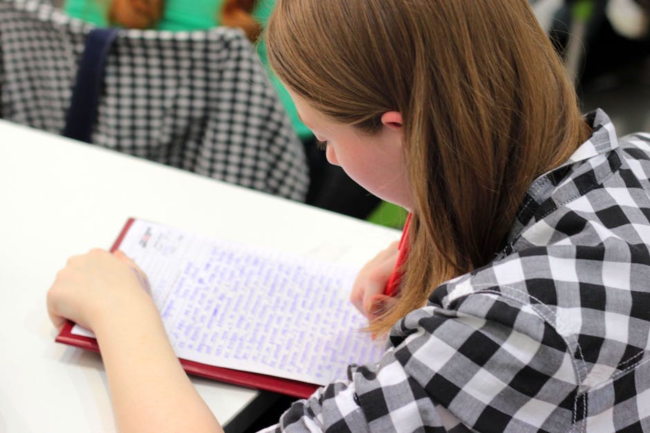 A young student writing in a notebook during a study session indoors